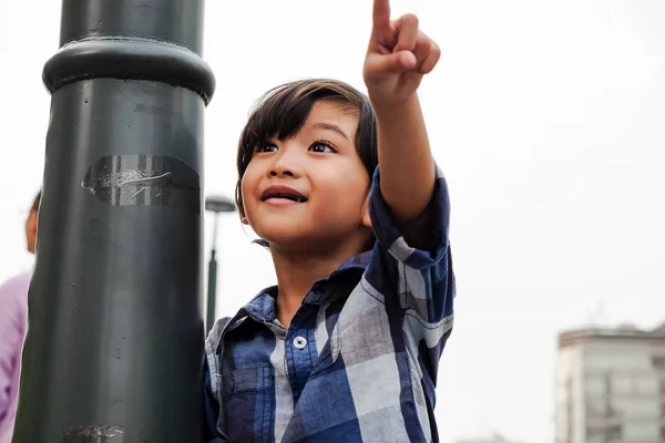 Asiático chico feliz apuntando a la ciudad escena dando algunos dirección —  Fotos de Stock