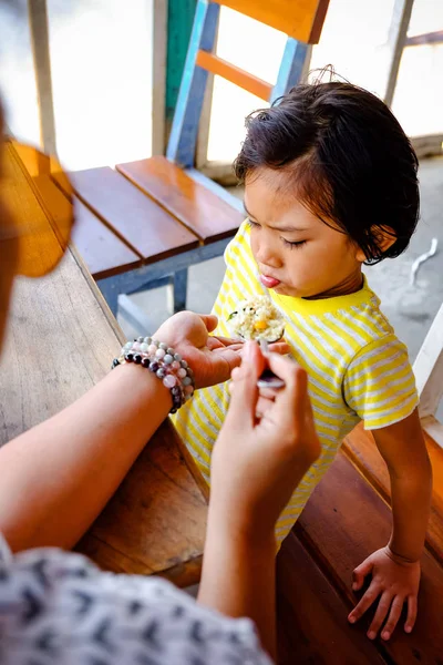 Asiático chico mostrando cruda facial expresión mientras siendo alimentado por su madre — Foto de Stock