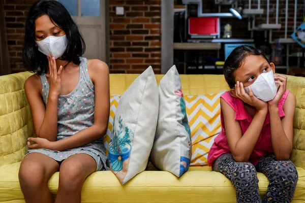 Südostasiatische Kleine Mädchen Mit Gesichtsmaske Sitzen Nebeneinander Auf Dem Sofa — Stockfoto