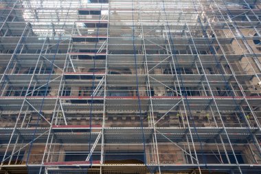 A building under construction - several story highs - covered with scafolding.   clipart