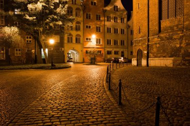 Night in the city of Gdansk in Poland, cobblestone street and square in the Old Town, next to the St. Mary's Church clipart
