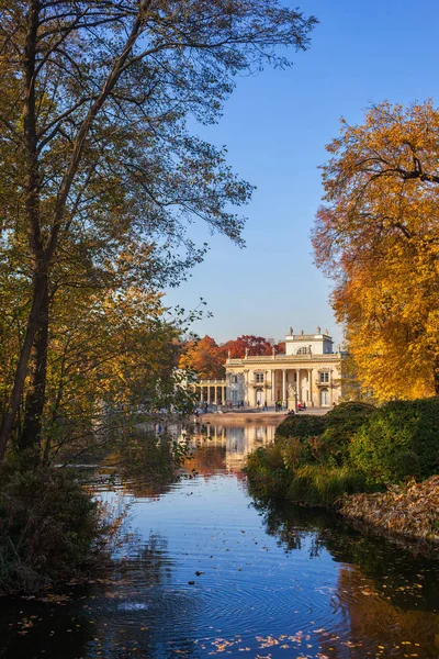 Lazienki Park in Warsaw, Poland, lake and autumn foliage scenery with Palace on the Isle or Palace on the Water, city landmark from 17th century.