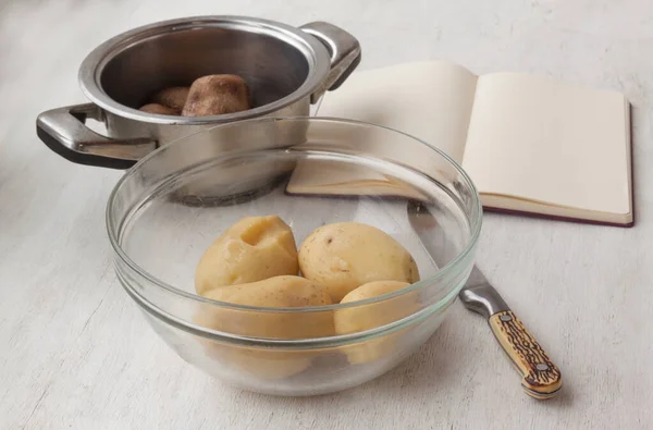 放在透明的碗里 放在锅子和写药方的书的后面 把烤好的土豆放在锅里 — 图库照片