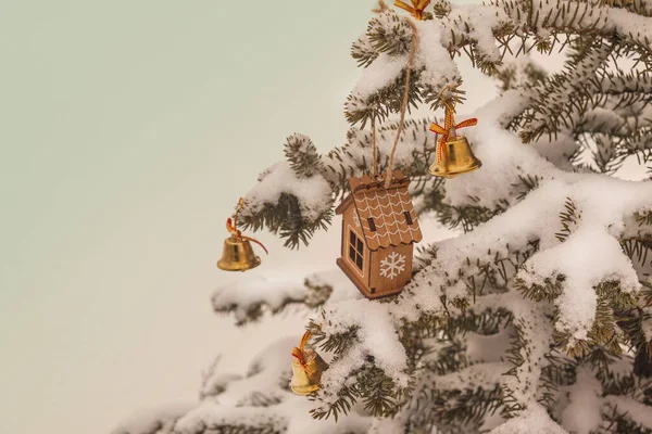 雪に覆われたクリスマスツリーのおもちゃの家と鐘 年賀状の背景 — ストック写真