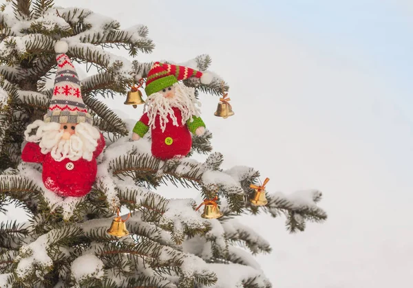 雪に覆われたクリスマスツリーと鐘の上に2つの陽気なおもちゃのノーム 大量生産 — ストック写真