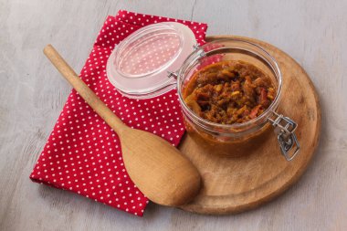 Elma, domates, soğan ve baharat kavanozunu gri bir masada yuvarlak bir kesim tahtasında aç..