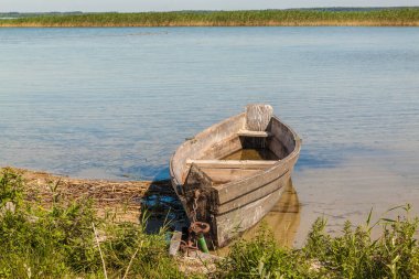 Güneşli bir günde Svitiaz Gölü 'nde (Shatsky Ulusal Doğal Parkı) sazlıkların arka planında eski bir tekne