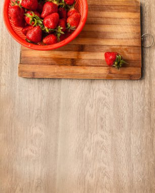 Ahşap bir masada kevgir şeklinde çilek. Düz Yat.