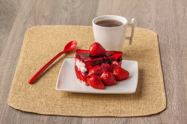 Cheesecake with berries strawberries and a cup with a cold drink on a wooden table.