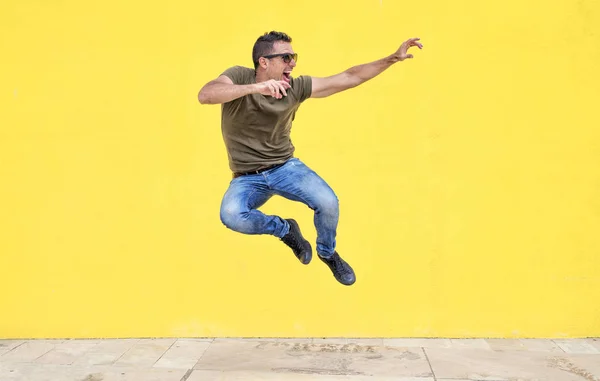 Vista Frontal Jovem Homem Feliz Usando Óculos Sol Saltando Contra — Fotografia de Stock