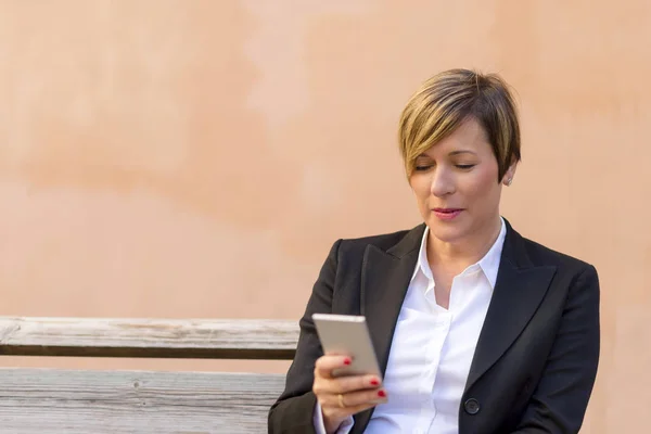 Vista Frontal Una Elegante Mujer Negocios Sonriente Sentada Banco Mientras — Foto de Stock