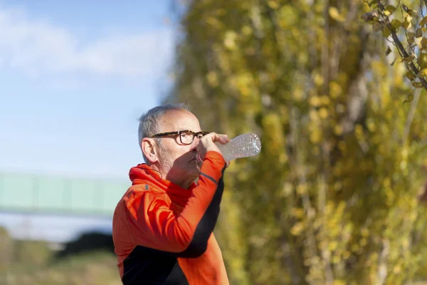 Μερική άποψη του ένας ανώτερος άνθρωπος αναπαύεται και το πόσιμο νερό μετά την προπόνηση, ενώ ψάχνει μακριά — Φωτογραφία Αρχείου