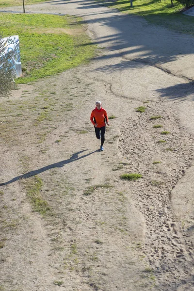 在阳光明媚的日子里, 一个老人在公园里慢跑 — 图库照片