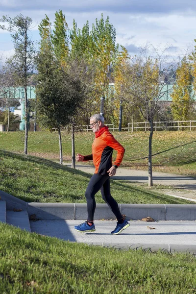 Side view of one senior caucasian athlete man training running up and down the stairs outdoors in a park in a sunny day