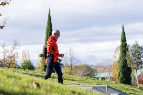 Side view of one senior caucasian athlete man training running up and down the stairs outdoors in a park in a sunny day — Stock Photo, Image