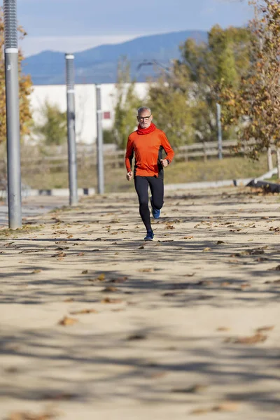 Framsida av en ledande man i sportkläder jogging i en stadspark i en solig dag — Stockfoto