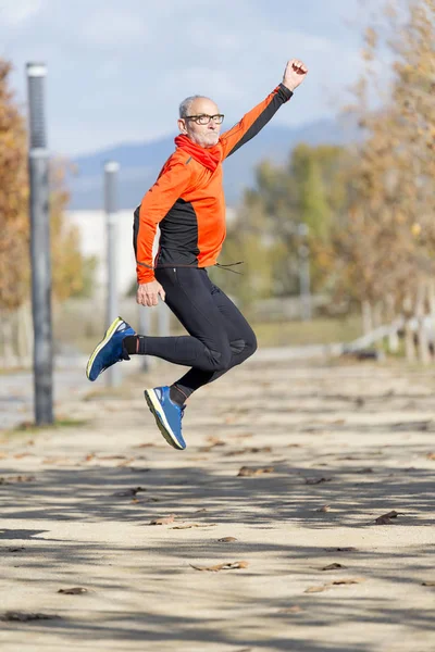 Senior runner man jumping arms up after running — Stock Photo, Image