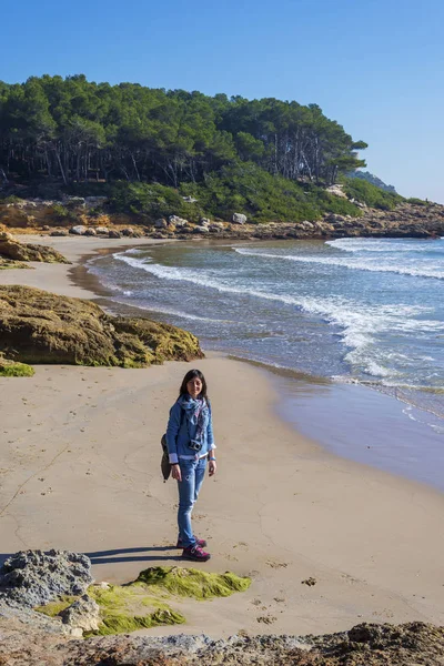 Above view of a young woman wearing casual clothes standing on the beach while looking to camera in a bright day — Stock Photo, Image