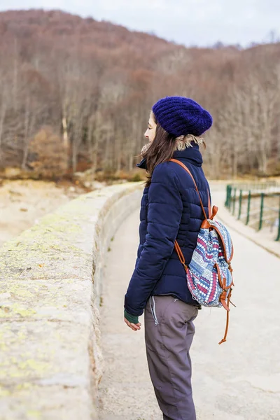 Sidovy av en ung backpacker kvinna stående medan du tittar bort i skogen — Stockfoto