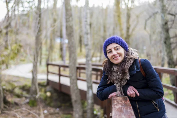 Front view portrait of a smiling beautiful girl with backpack standing near old footbridge — Stock Photo, Image