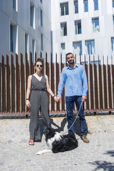 一对夫妇站在城市与狗在阳光明媚的一天 — 图库照片