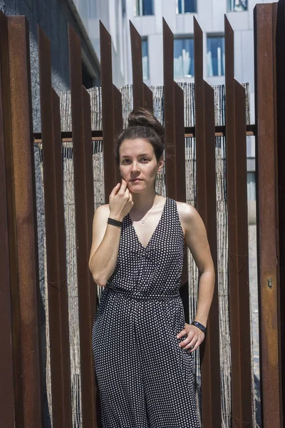 Csinos, fiatal, stílusos nő álló kerítés ellen — Stock Fotó