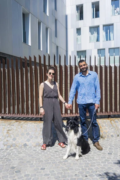Пара стоящих в городе с собакой в ясный день — стоковое фото