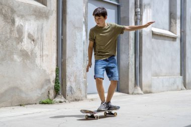 Güneşli bir günde şehre binen neşeli patenci çocuğun ön görünümü