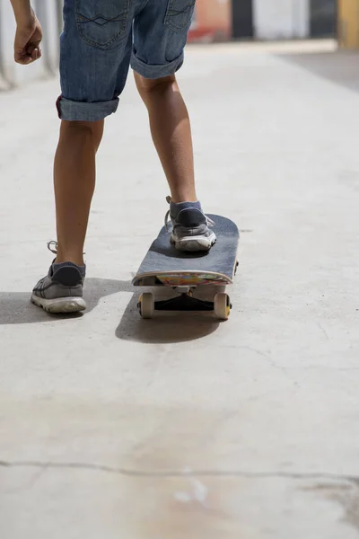 Bakifrån av unga skateboardåkare ben ridning på skateboard — Stockfoto