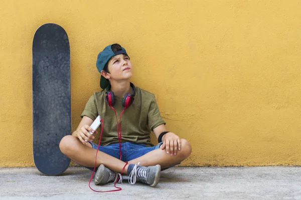 Front view of a young boy sitting on ground leaning on a yellow — Stock Photo, Image