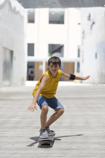 Front view of cheerful skater boy riding on the city in a sunny day — Stock Photo, Image