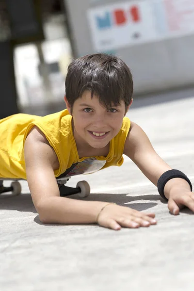 Young smiling boy on a skateboard while looking camera on a bright day — 스톡 사진