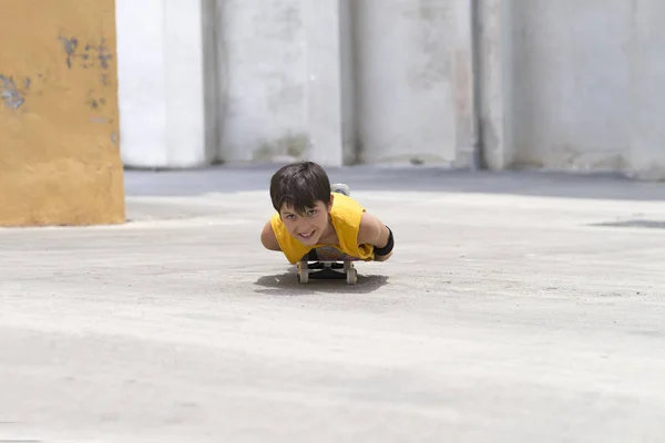 明るい日にカメラを見ながらスケートボード上の若い笑顔の男の子 — ストック写真