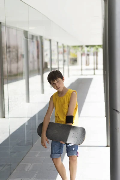 Young boy holding a skateboard outdoors in a bright day — Stock Photo, Image