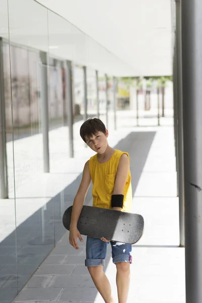 Ung pojke håller en skateboard utomhus i en ljus dag — Stockfoto