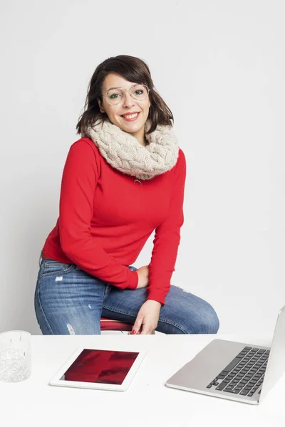 Vooraanzicht van een mooie vrouw in casual slijtage zittend op een kruk terwijl op zoek camera tegen witte achtergrond — Stockfoto