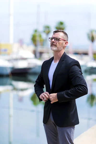 Mature businessman standing in the city looking sideways — Stock Photo, Image