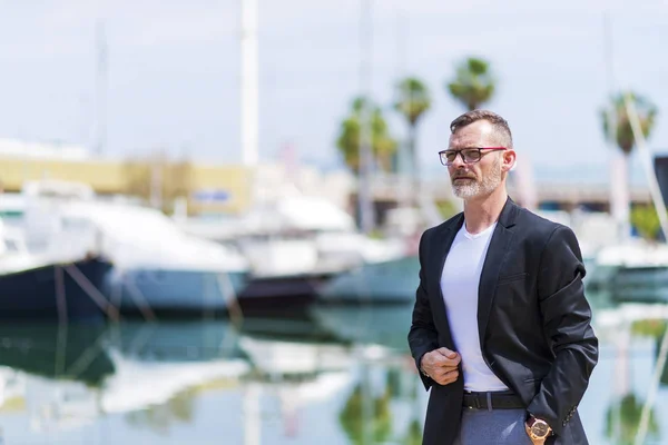 Uomo d'affari in piedi in città mano sulla tasca, mentre guardando altrove e sorridendo . — Foto Stock