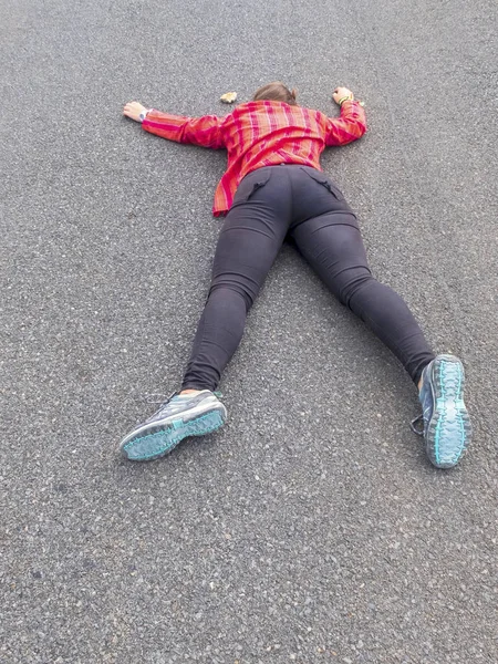 Woman lying face down injured on a road