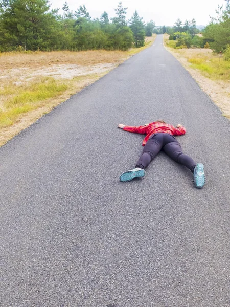 Mulher deitada em uma estrada após o acidente — Fotografia de Stock