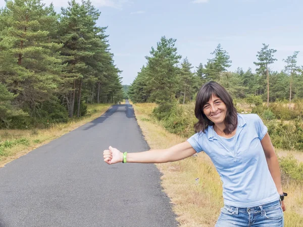 Hitchhiking meisje. Mooi meisje staande op een snelweg en het vangen van een voorbijgaand auto. — Stockfoto