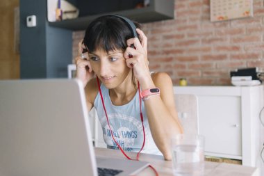 Headp ile müzik dinlerken evde çalışan dizüstü bilgisayar ile kadın