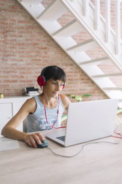 Headp ile müzik dinlerken evde çalışan dizüstü bilgisayar ile kadın