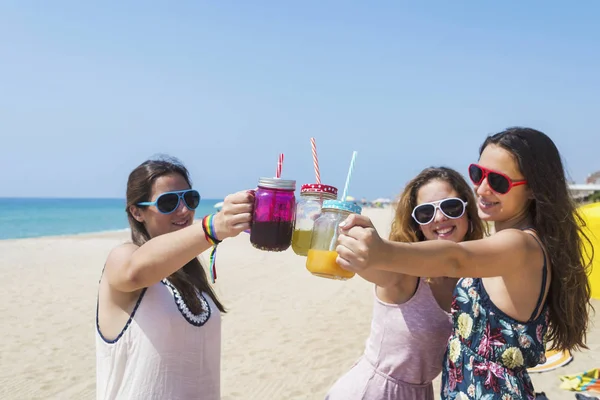 Gruppe fröhlicher junger Frauen oder Freundinnen, die am Sommerstrand auf alkoholfreie Getränke anstoßen — Stockfoto