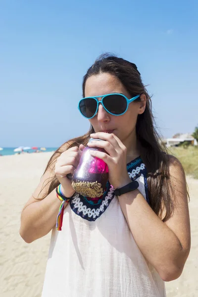Uma jovem garota bronzeada veio ao resort, usa um vestido elegante e óculos de sol, segura uma deliciosa bebida de suco na mão . — Fotografia de Stock
