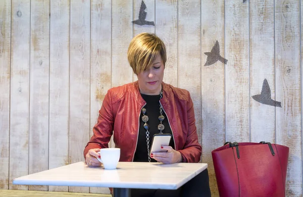 Молодая женщина пишет смс по телефону в кафе — стоковое фото