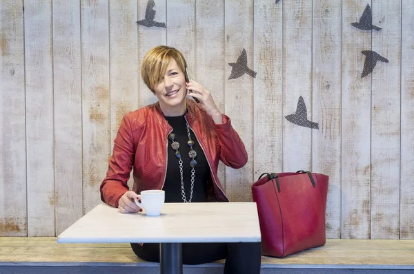 Mooie blonde vrouw praten op mobiele telefoon terwijl zittend in een café — Stockfoto