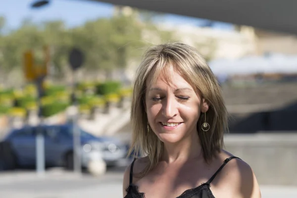 Retrato de cerca de una mujer rubia con los ojos cerrados mientras sonríe al aire libre — Foto de Stock