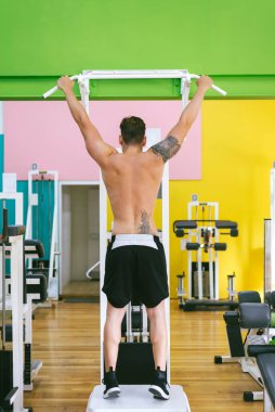 Spor salonundaki barlarda barfiks çeken kaslı adam spor salonunda çalışan adam..