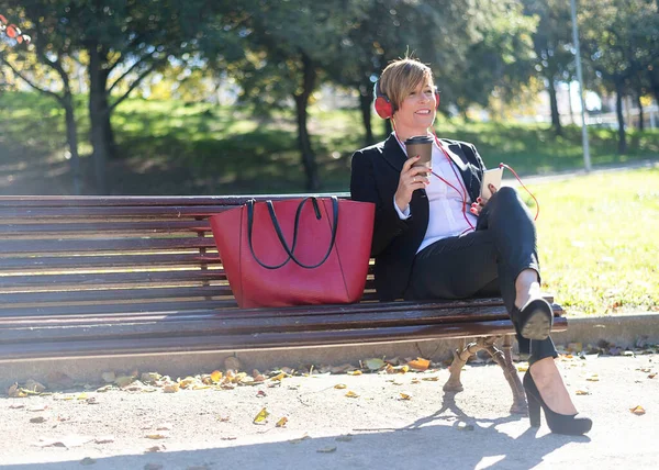 Mulher Negócios Sorridente Sentada Banco Parque Enquanto Ouve Música Por — Fotografia de Stock